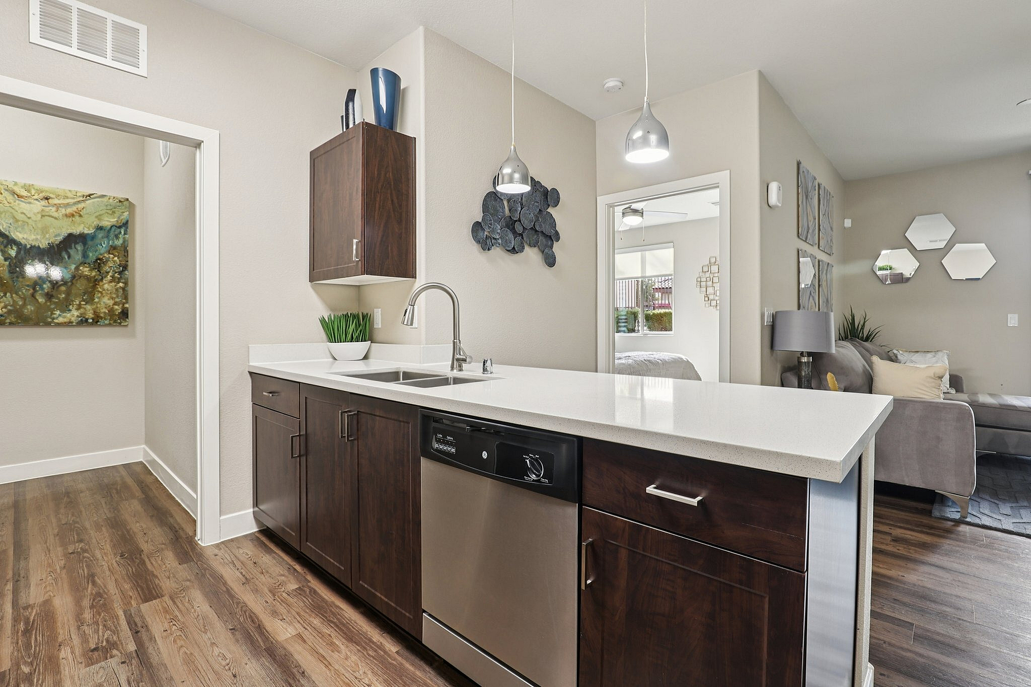 Modern kitchen with sleek countertops, elegant pendant lighting, and cozy living area with artistic decor.