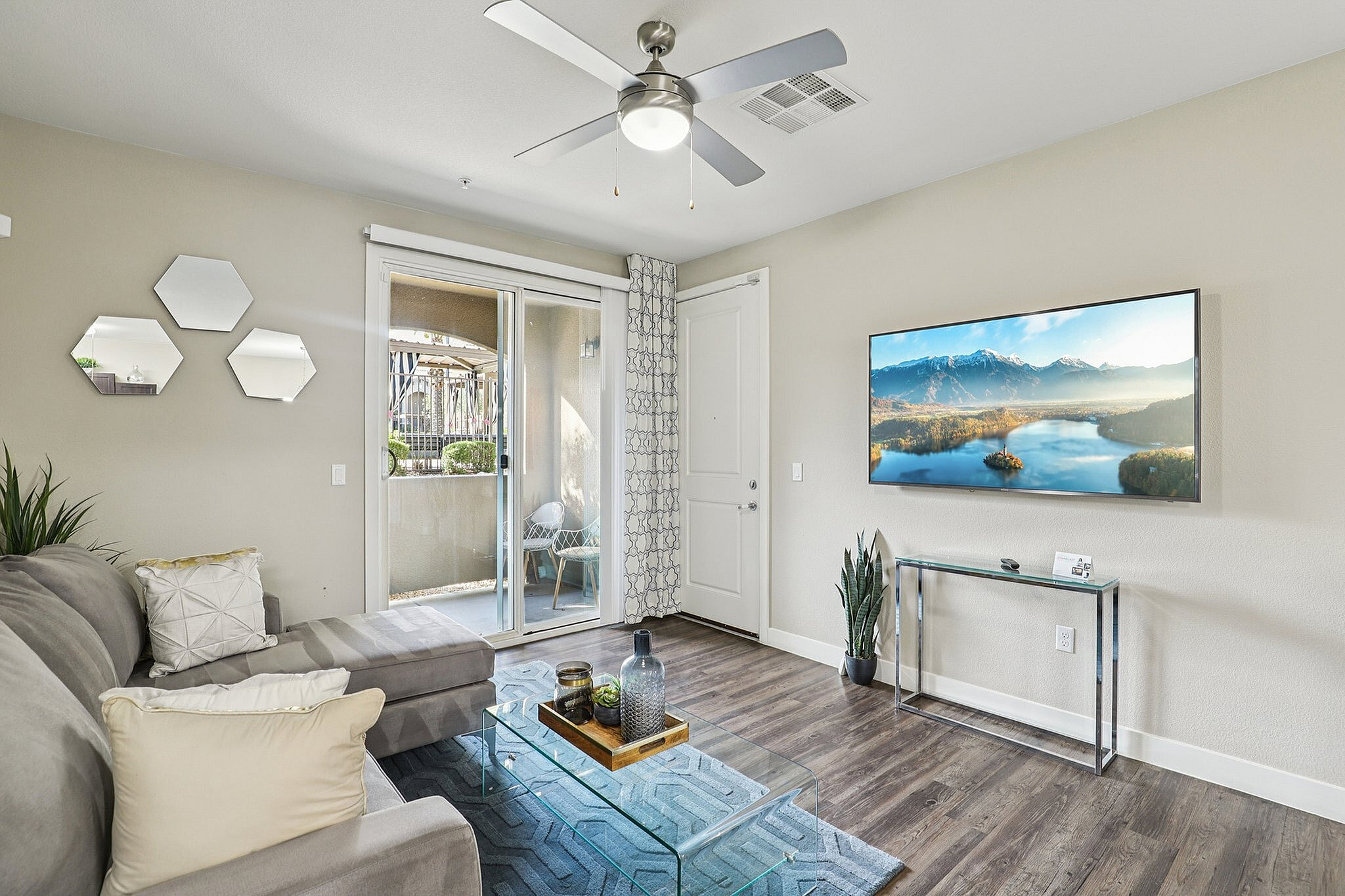 Bright, modern living room with stylish decor, featuring a plush sofa, glass coffee table, and a flat-screen TV. Opens onto a charming balcony for relaxing outdoor moments.