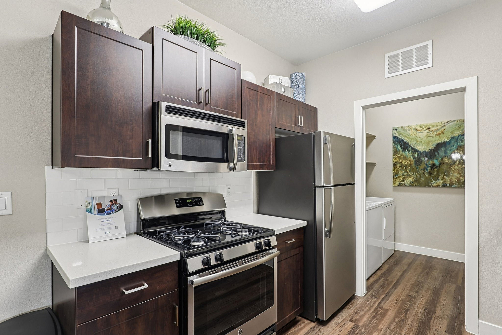 Modern kitchen with sleek stainless steel appliances, elegant dark wood cabinets, and bright white countertops, exuding a chic contemporary vibe.