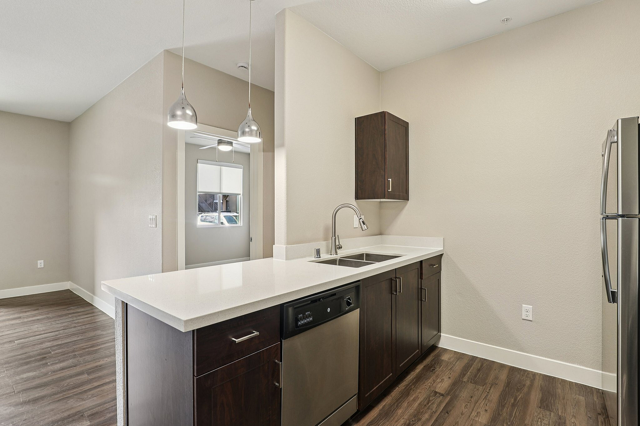 Modern kitchen design featuring dark wood cabinets, sleek stainless steel appliances, and a spacious white countertop with stylish pendant lighting.
