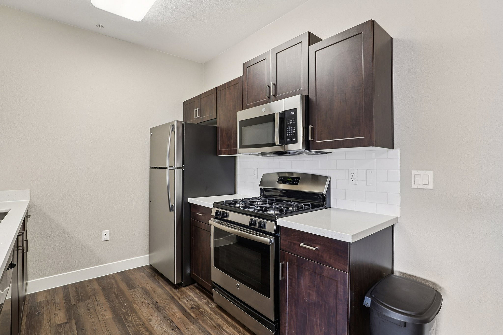 Modern kitchen with sleek stainless steel appliances, elegant dark wood cabinetry, and pristine countertops.