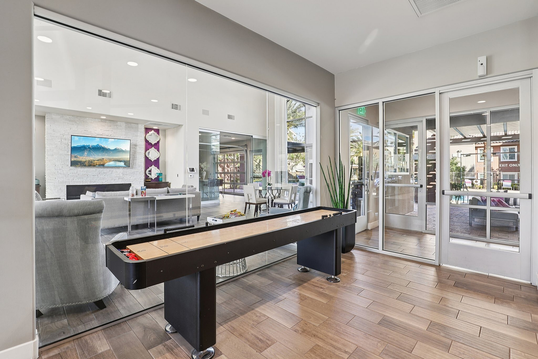 Luxurious game area with modern shuffleboard, stylish seating, and vibrant decor in a bright, open community space.