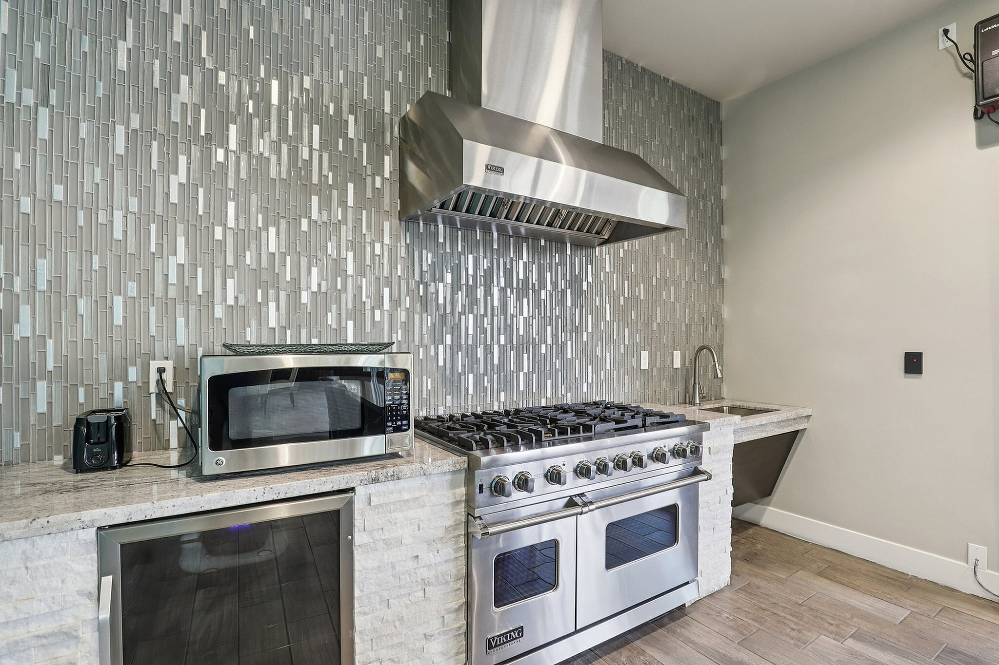 Modern kitchen with sleek stainless steel appliances, mosaic tile backsplash, and elegant countertops.