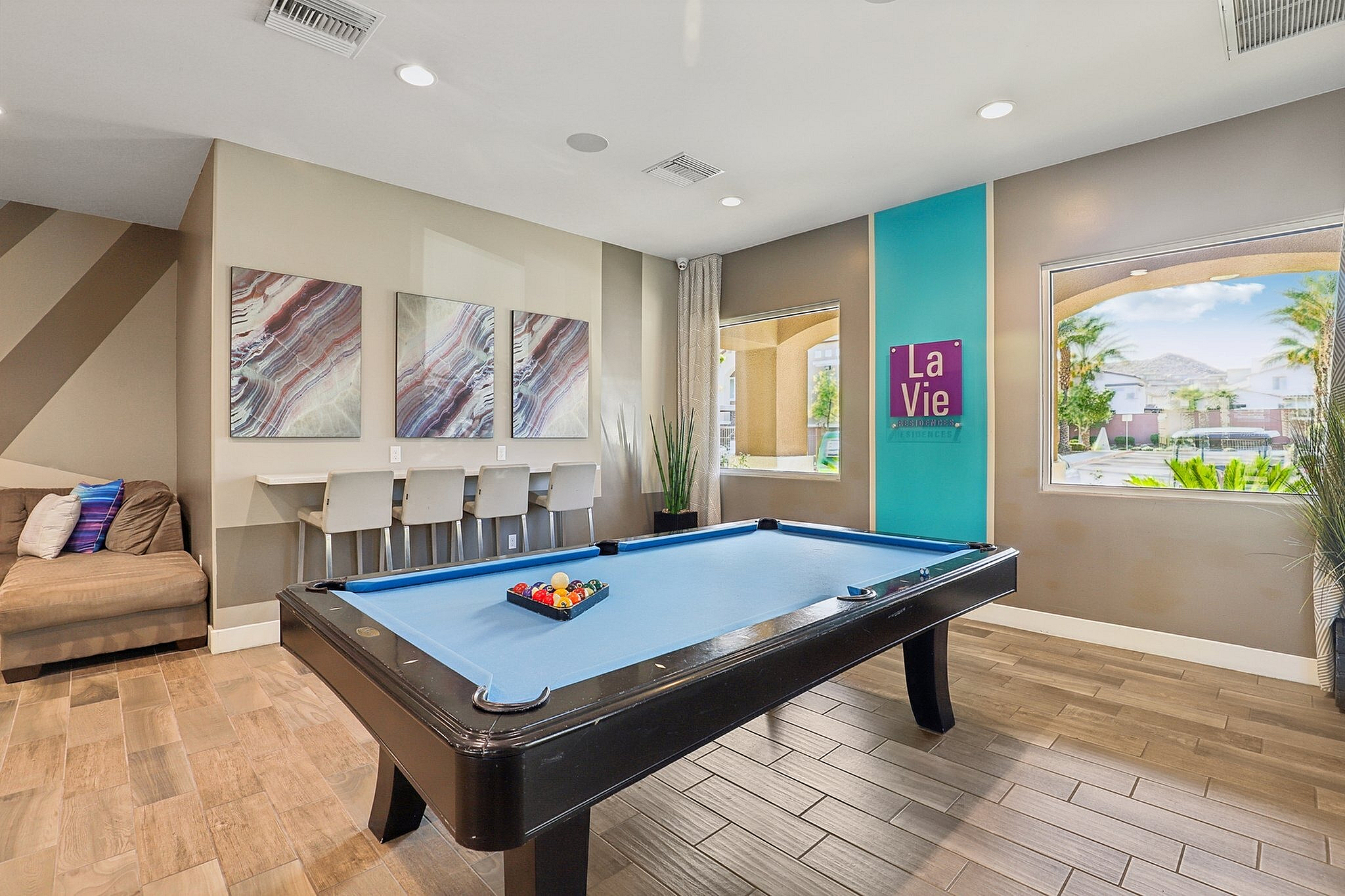Chic recreational room with a vibrant pool table, modern decor, and inviting lounge seating overlooking scenic outdoor views.