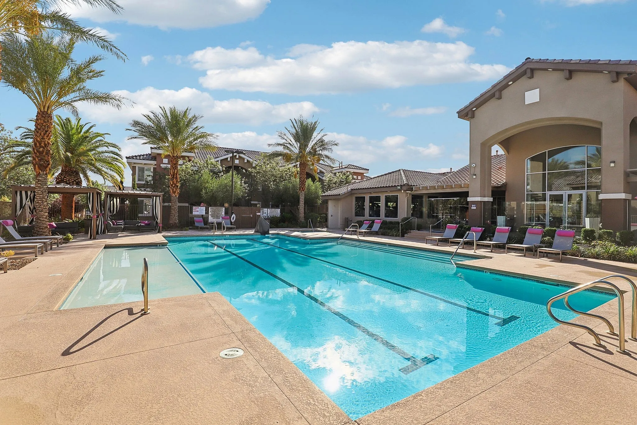 Gorgeous resort-style swimming pool surrounded by palm trees and luxurious loungers, perfect for relaxation and leisure.