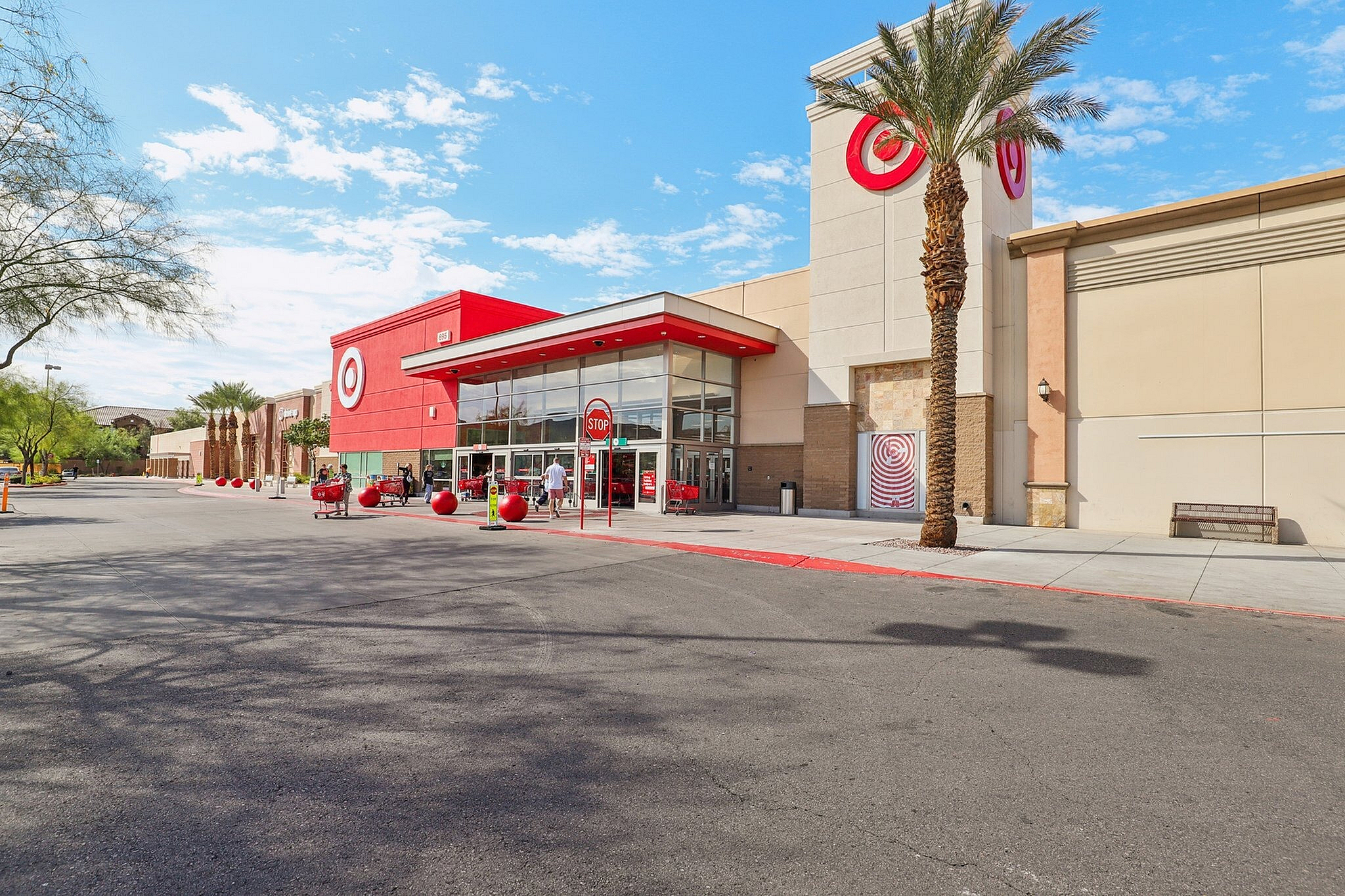 Vibrant outdoor view of a popular retail store with bold red accents, modern architecture, and welcoming palm trees under a bright blue sky.