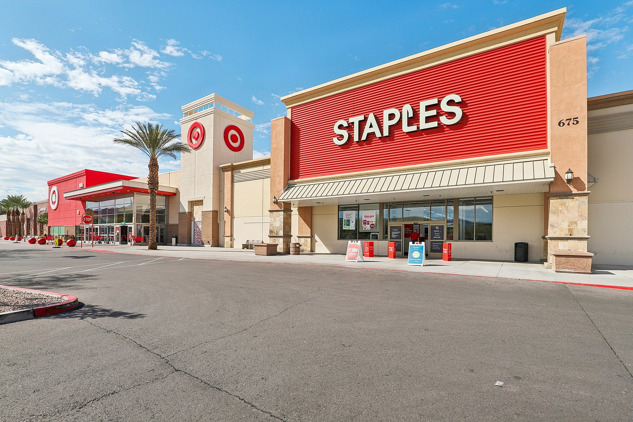 Vibrant shopping area featuring popular retail stores with striking architecture and palm trees under a bright blue sky.