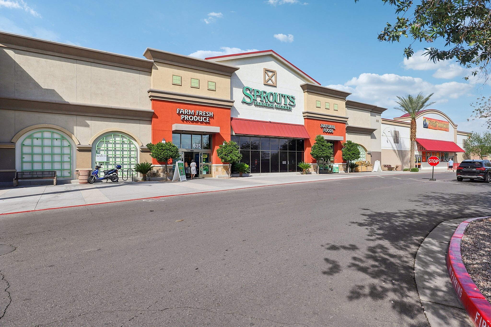 Inviting exterior of a modern grocery store with vibrant red accents, offering farm fresh produce and natural foods.