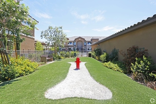 Inviting apartment exterior surrounded by lush greenery and a vibrant courtyard path leading to a charming entrance.