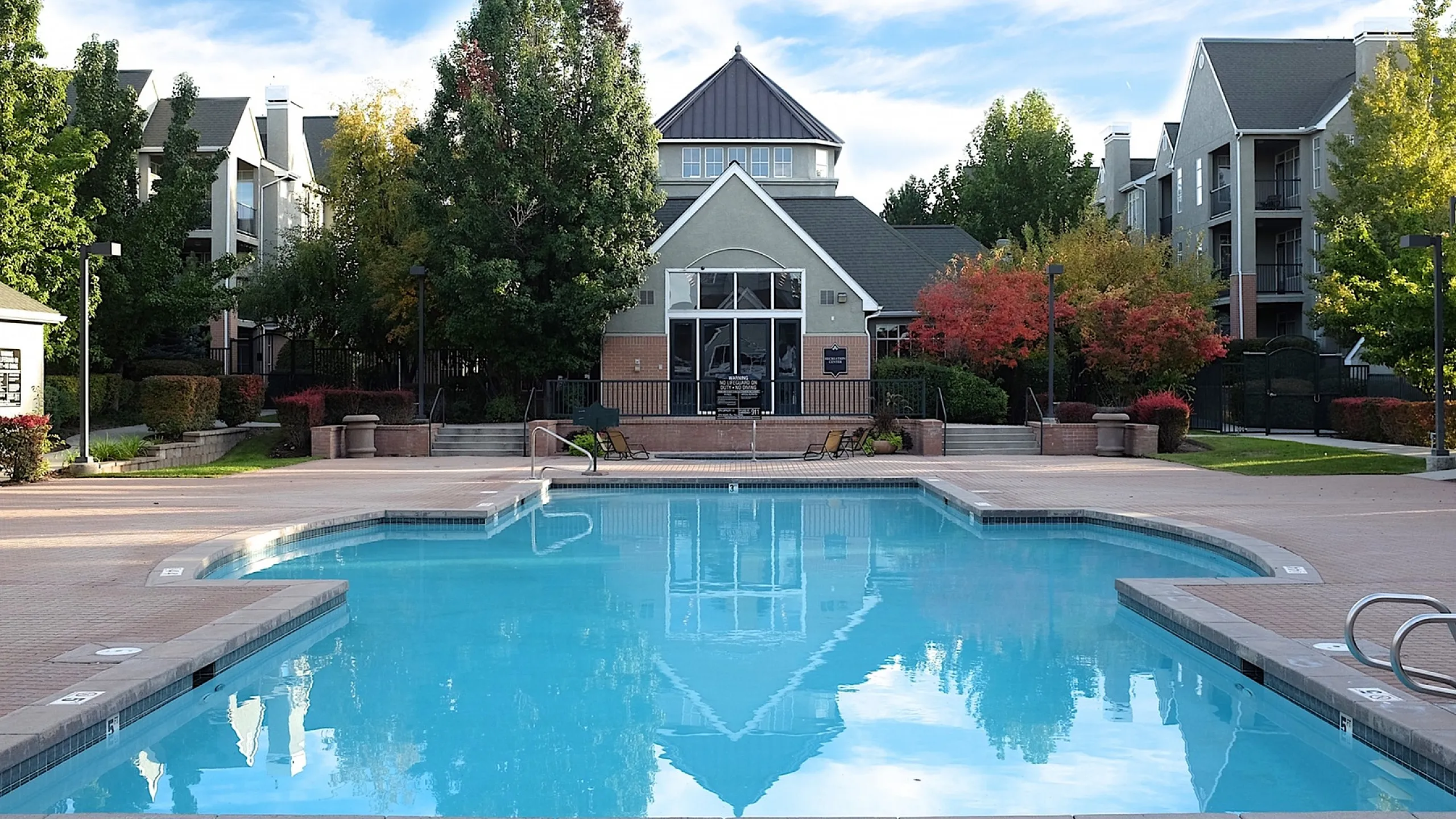 Inviting outdoor pool area surrounded by lush greenery and modern apartment buildings.