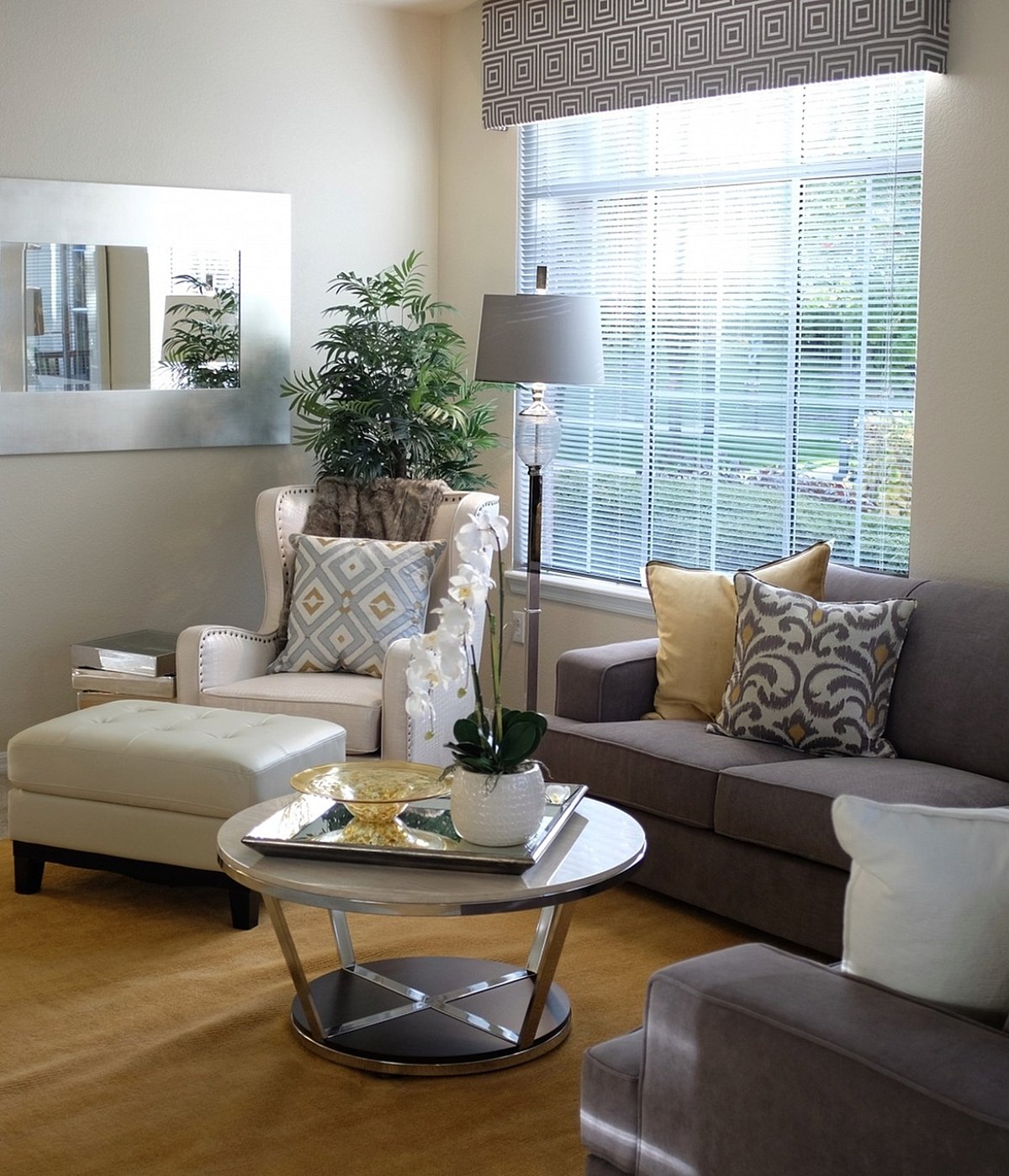 Bright and inviting living room with modern decor, featuring a plush grey sofa, stylish armchair, large window, and decorative accents.