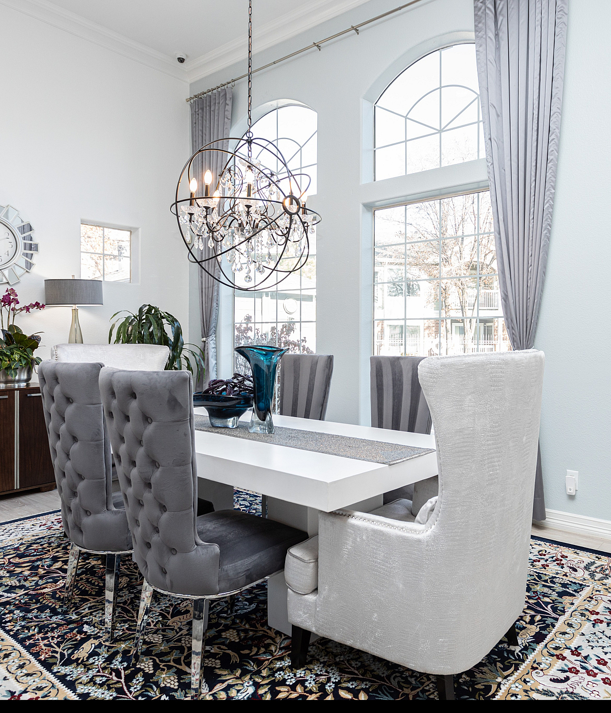 Stylish dining room with modern chandelier, plush chairs, and large windows.