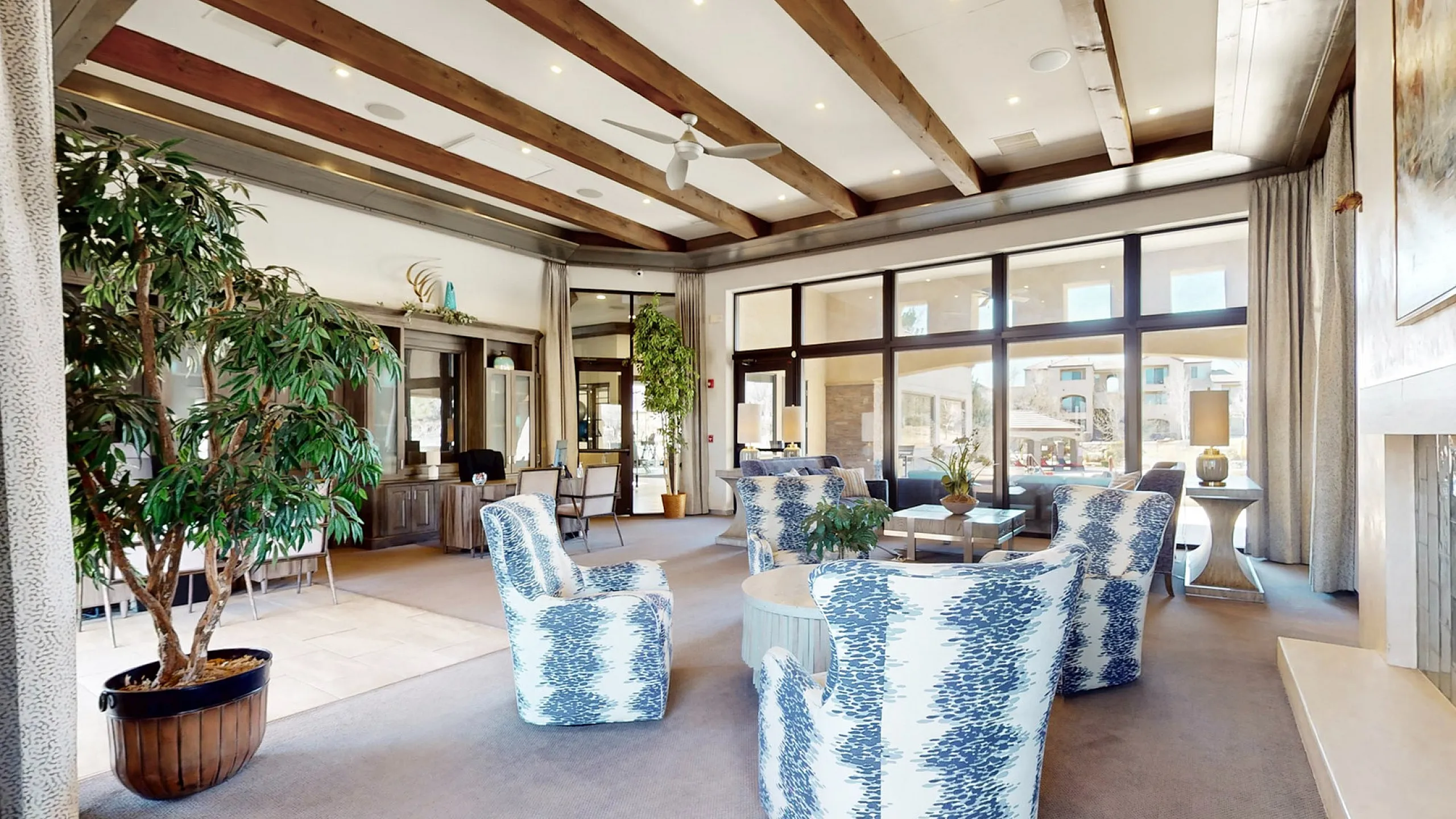 Luxurious lounge space with modern furniture, large windows, and wooden ceiling beams.