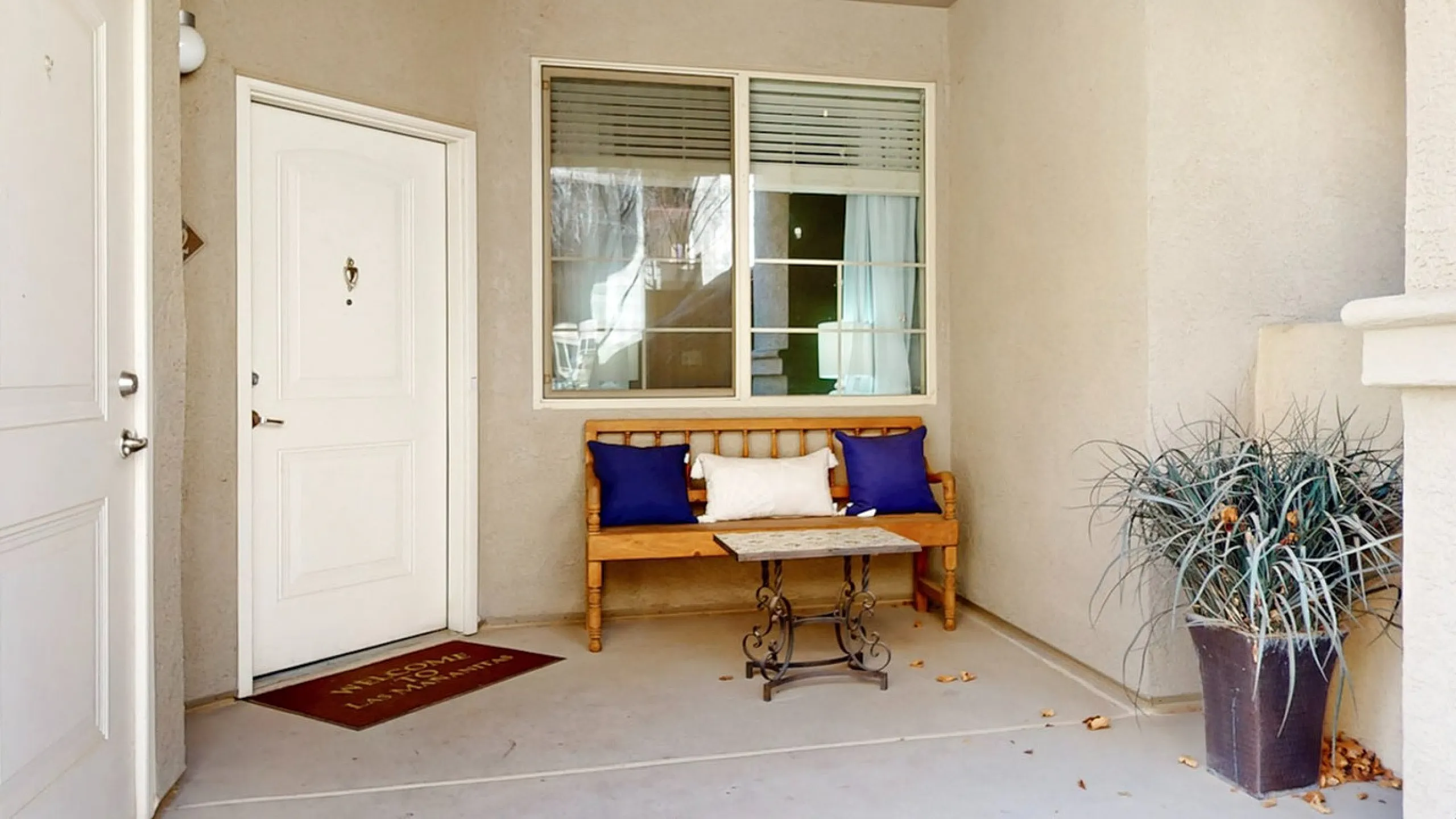 Welcoming apartment entrance with cozy seating, potted plant, and decorative railing.