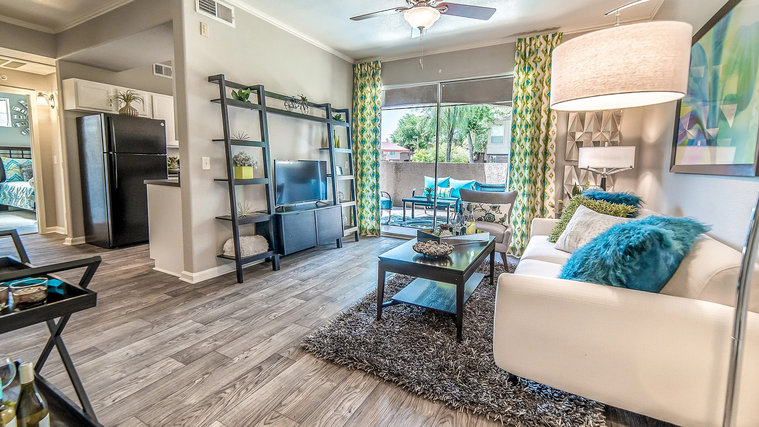 Bright and modern living room with stylish decor, featuring a cozy white sofa, vibrant throw pillows, and elegant lighting. The room opens to a scenic balcony with lush views, creating a seamless indoor-outdoor living experience.