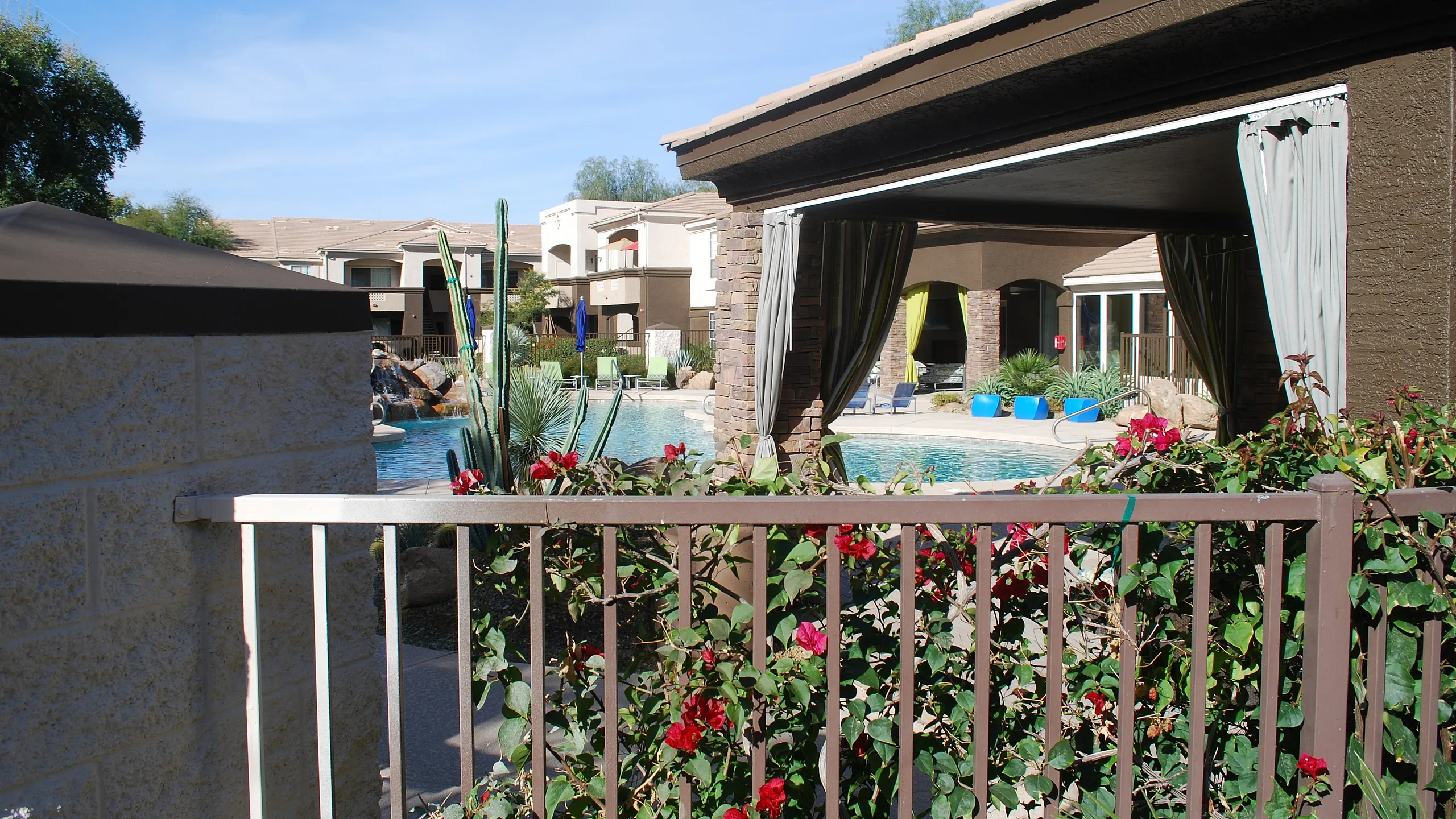 Upscale apartment complex with lush garden views overlooking a sparkling pool and elegant cabanas.