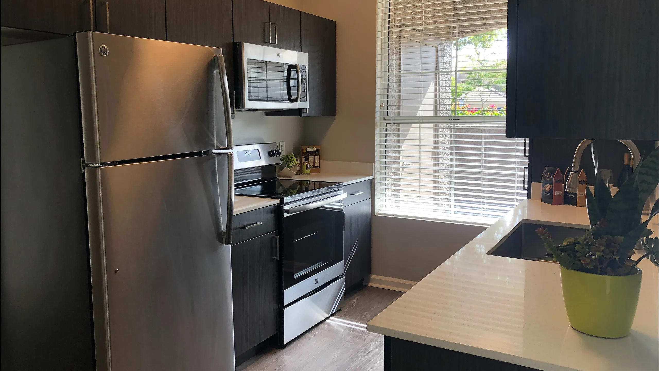 Modern kitchen with stainless steel appliances, sleek cabinets, and large window offering natural light.