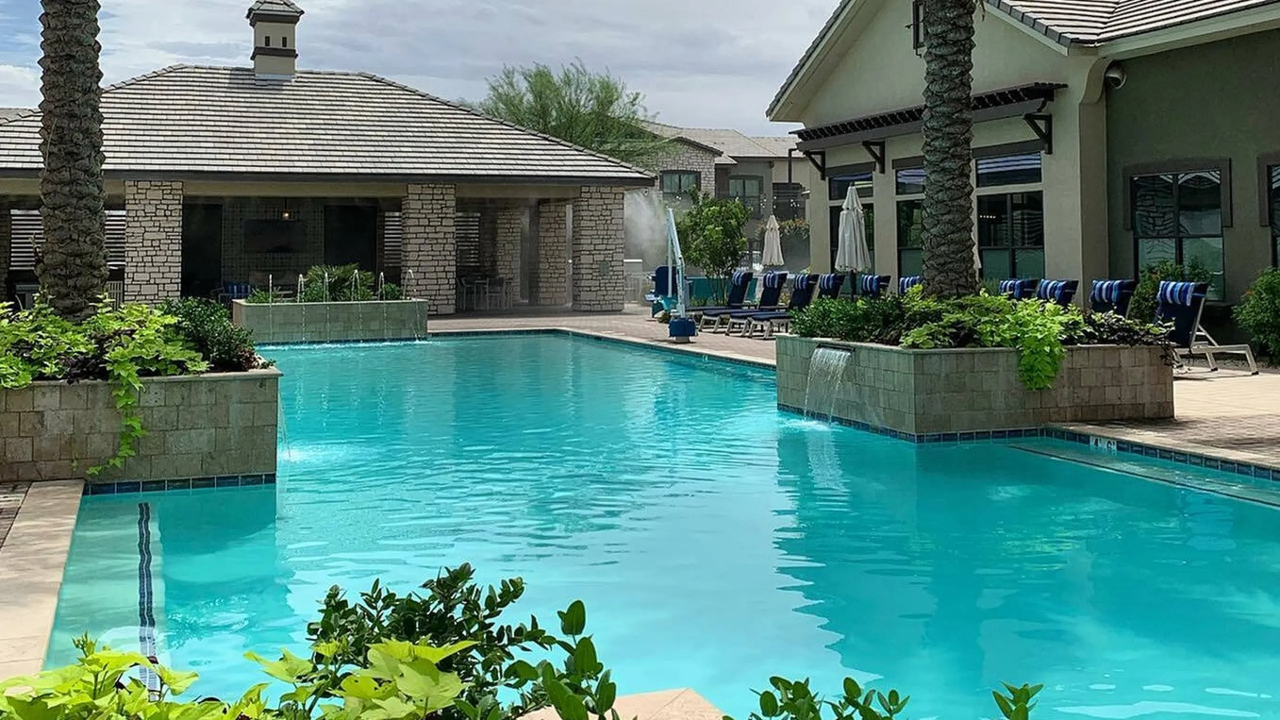 Luxurious apartment complex with inviting swimming pool, surrounded by lush greenery and palm trees, perfect for relaxation.