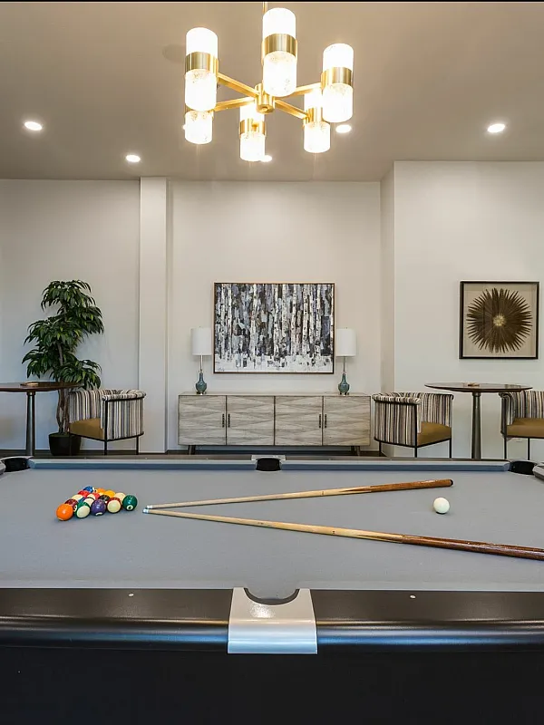 Elegant recreation room featuring a modern pool table, cozy seating area, and stylish decor under warm ambient lighting.
