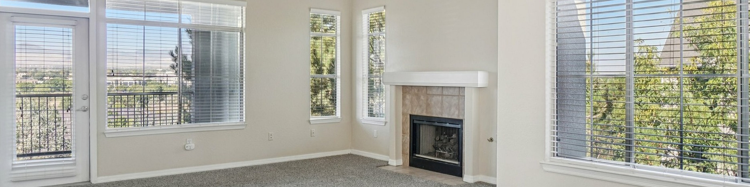 Bright, airy living room with plush carpeting, large windows offering scenic views, and a cozy fireplace for modern comfort.