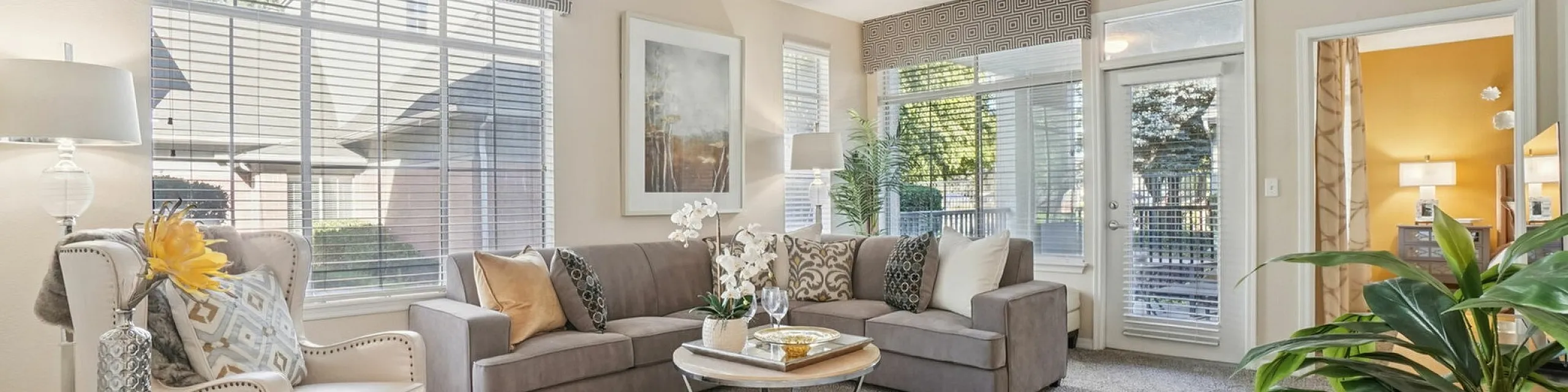 Bright and inviting living room with elegant decor, plush grey sofa, and large windows filling the space with natural light.
