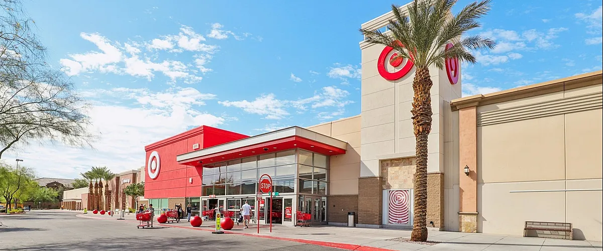 Vibrant exterior of a modern retail store featuring signature red accents and tall palm trees under a clear blue sky.