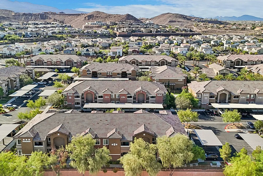 Stunning aerial view of a modern residential community with beautifully landscaped greenery and scenic mountain backdrop.