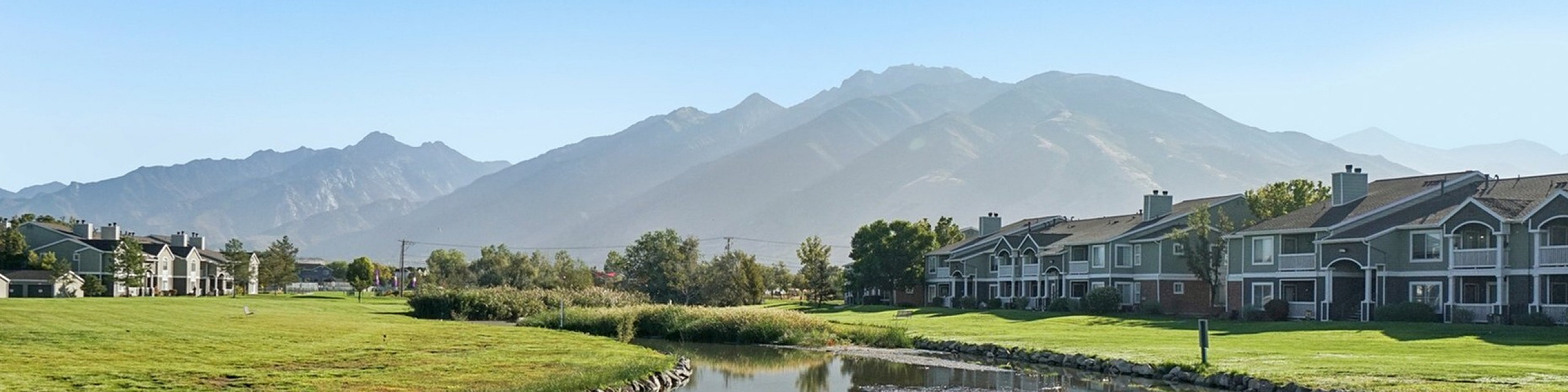 Charming riverside apartments with scenic mountain backdrop and lush green surroundings.
