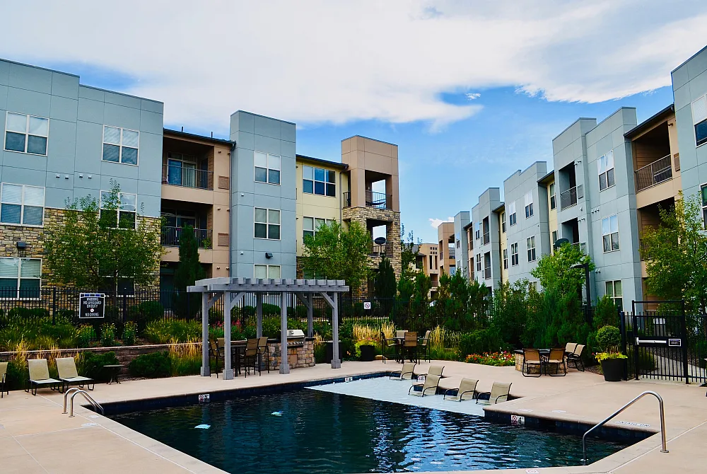 Modern apartment complex with stylish architecture, lush gardens, and a pristine swimming pool offering resort-like amenities.