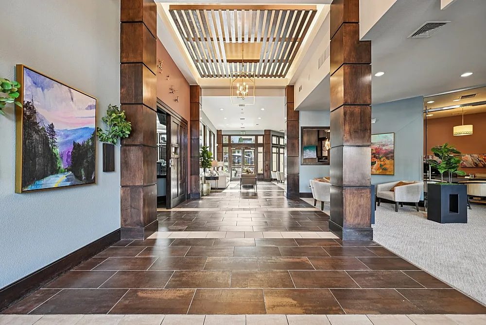 Luxurious apartment lobby with elegant wood accents, modern art, and comfortable seating areas creating an inviting atmosphere.