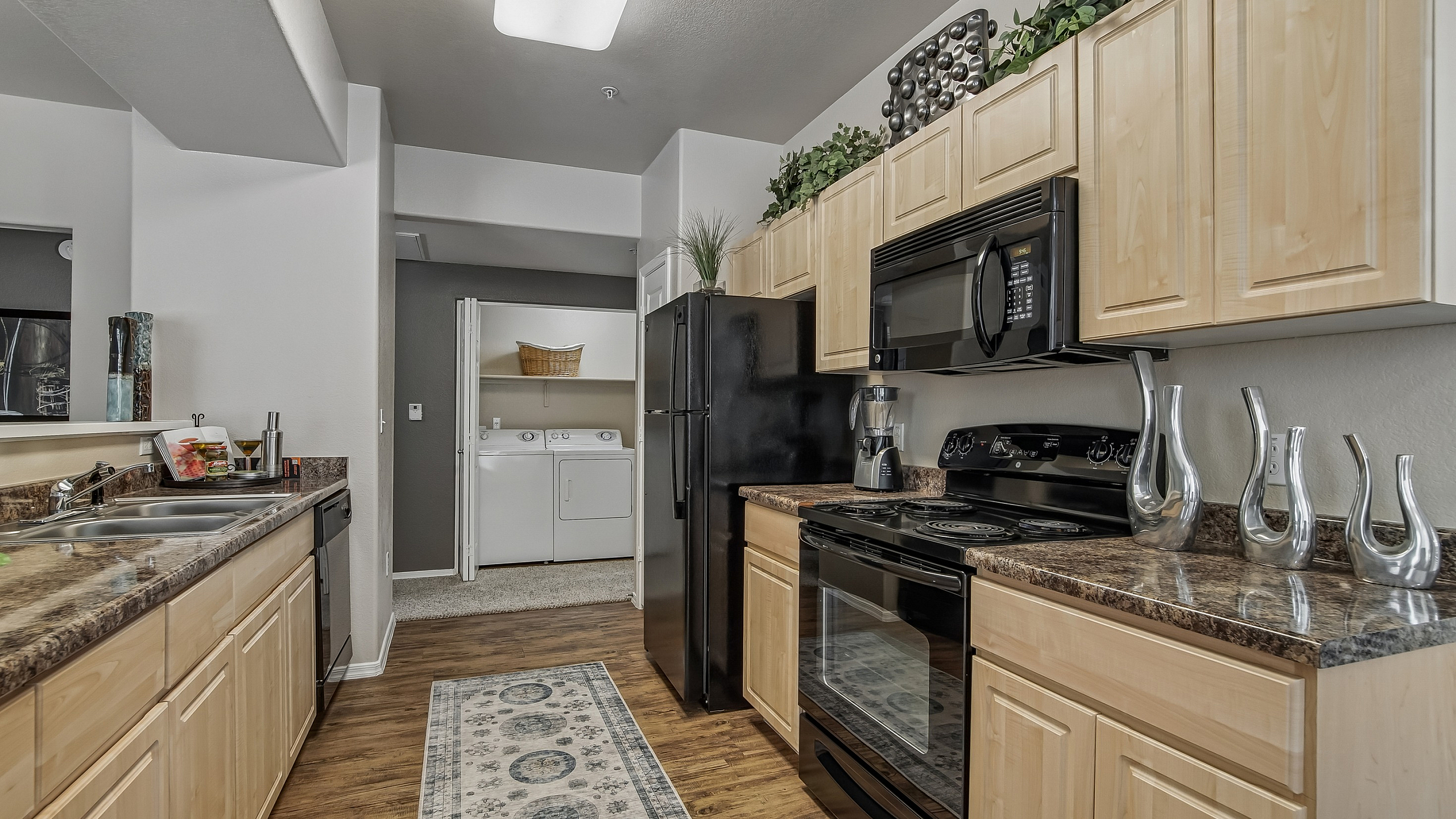 Modern kitchen with sleek appliances, abundant cabinetry, and stylish decor leading to an in-unit laundry area.