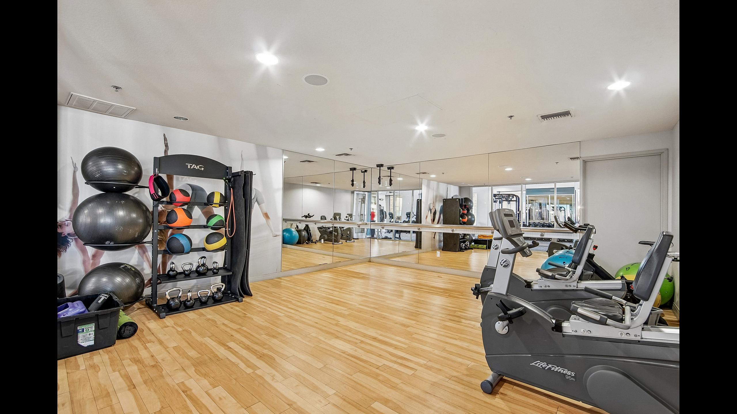 Modern fitness center featuring state-of-the-art exercise equipment, mirrored walls, and gleaming wood floors for an invigorating workout experience.