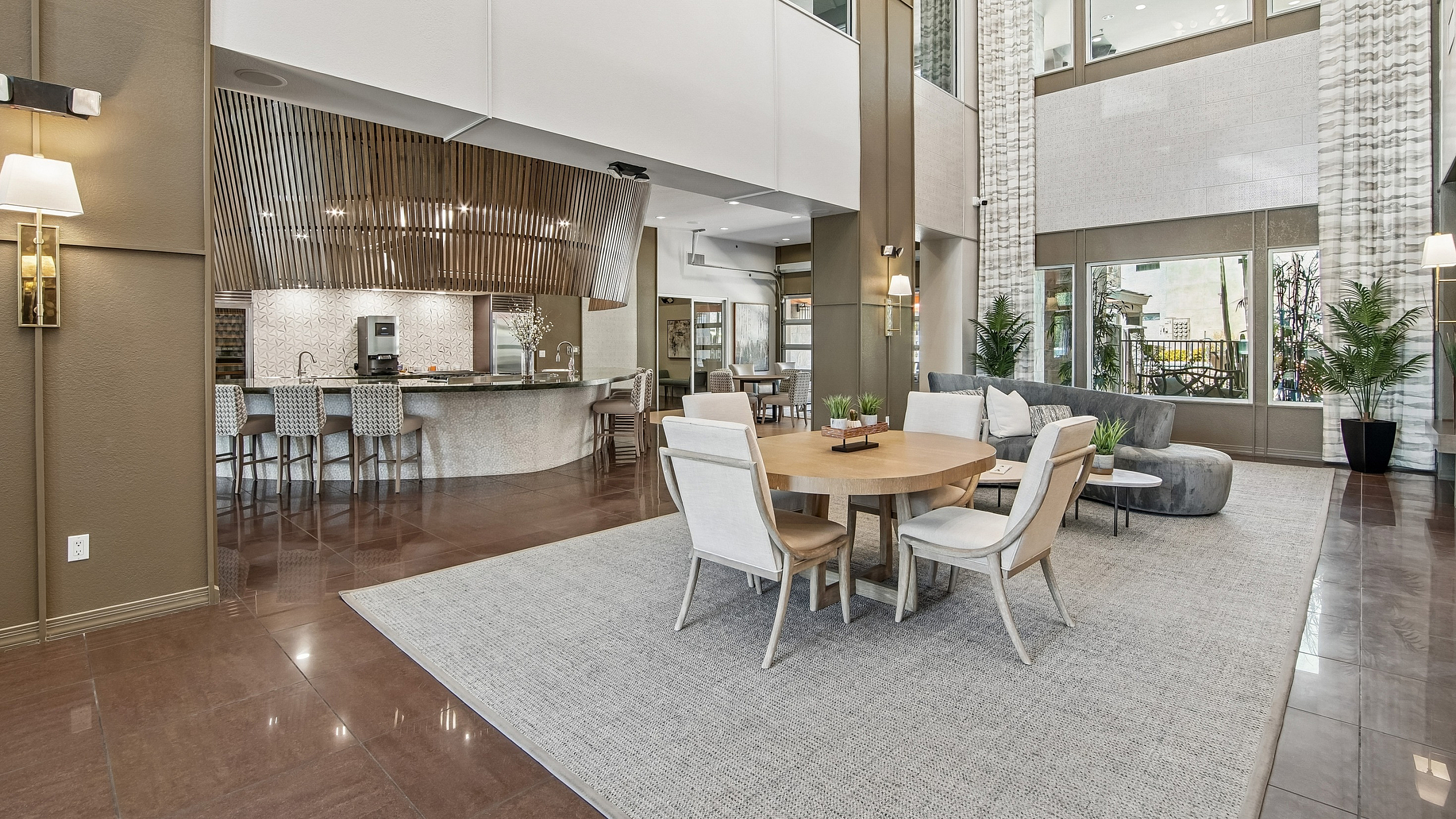 Luxurious apartment lobby with modern seating area, stylish bar, and elegant decor featuring large windows for natural light.