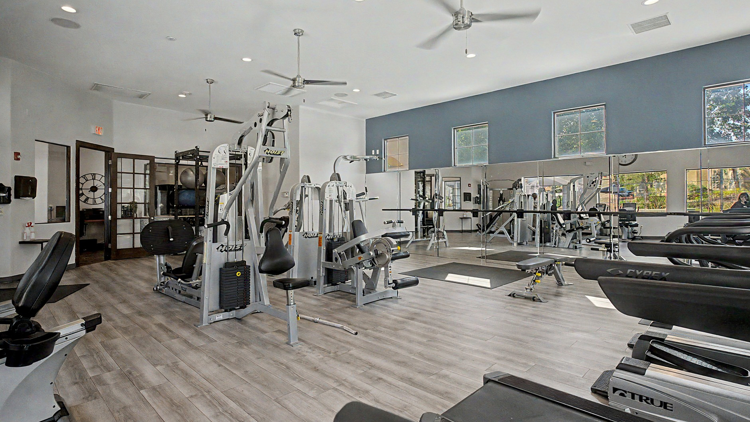 Modern fitness center with state-of-the-art exercise equipment, bright natural lighting, and spacious workout areas.