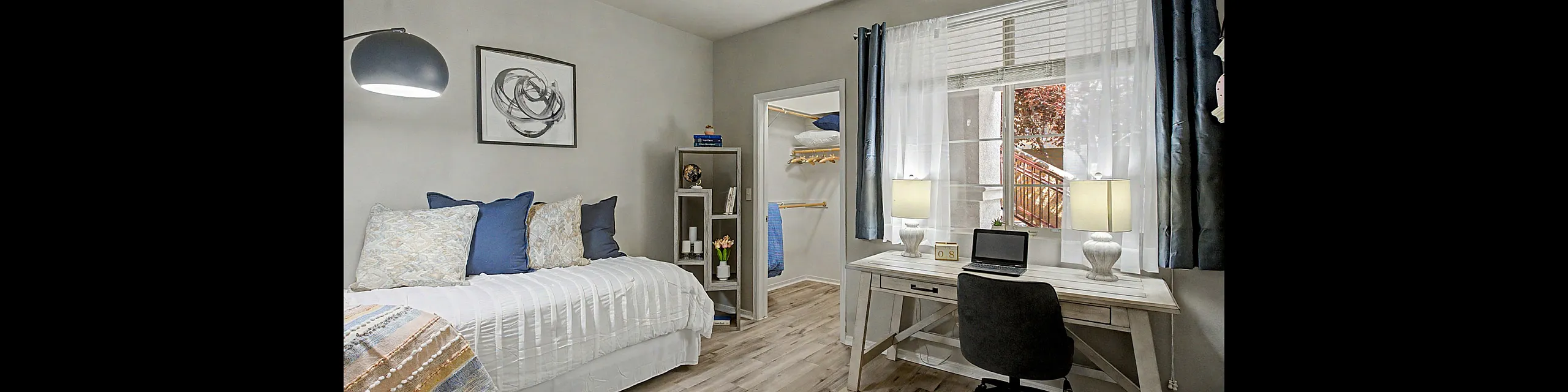 Charming and cozy bedroom featuring a stylish home office setup, modern decor, and an inviting window view.
