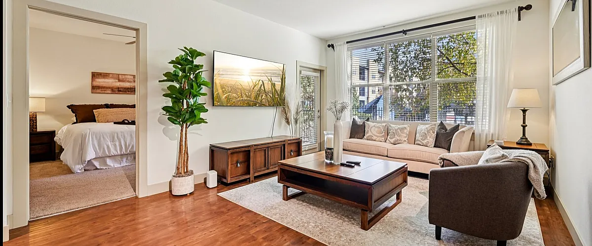 Inviting apartment interior with a bright living room, cozy seating, and elegant decor; includes a glimpse into the serene bedroom.