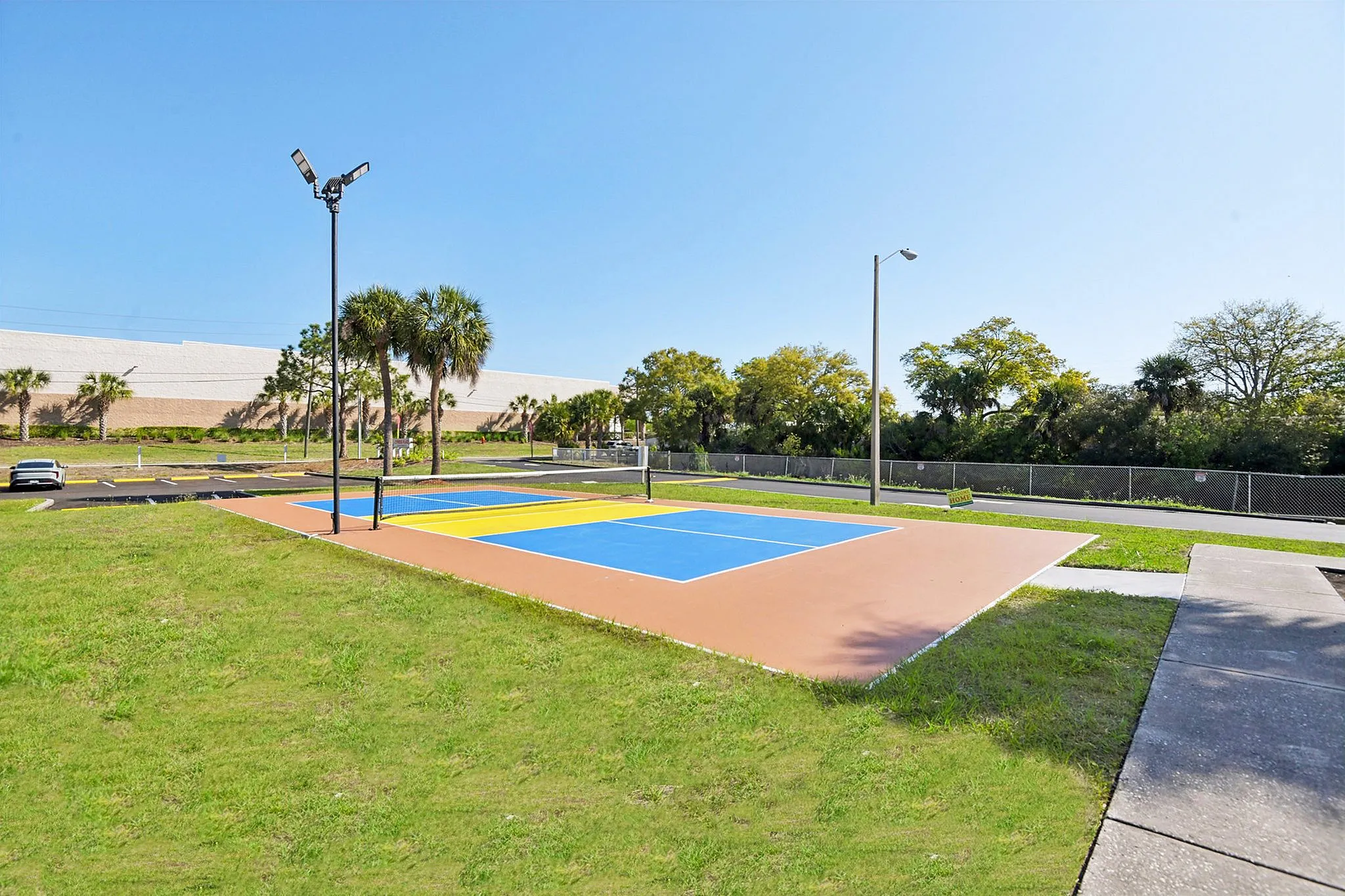 Vibrant outdoor sports court with blue and orange surfaces set against lush greenery and palm trees.
