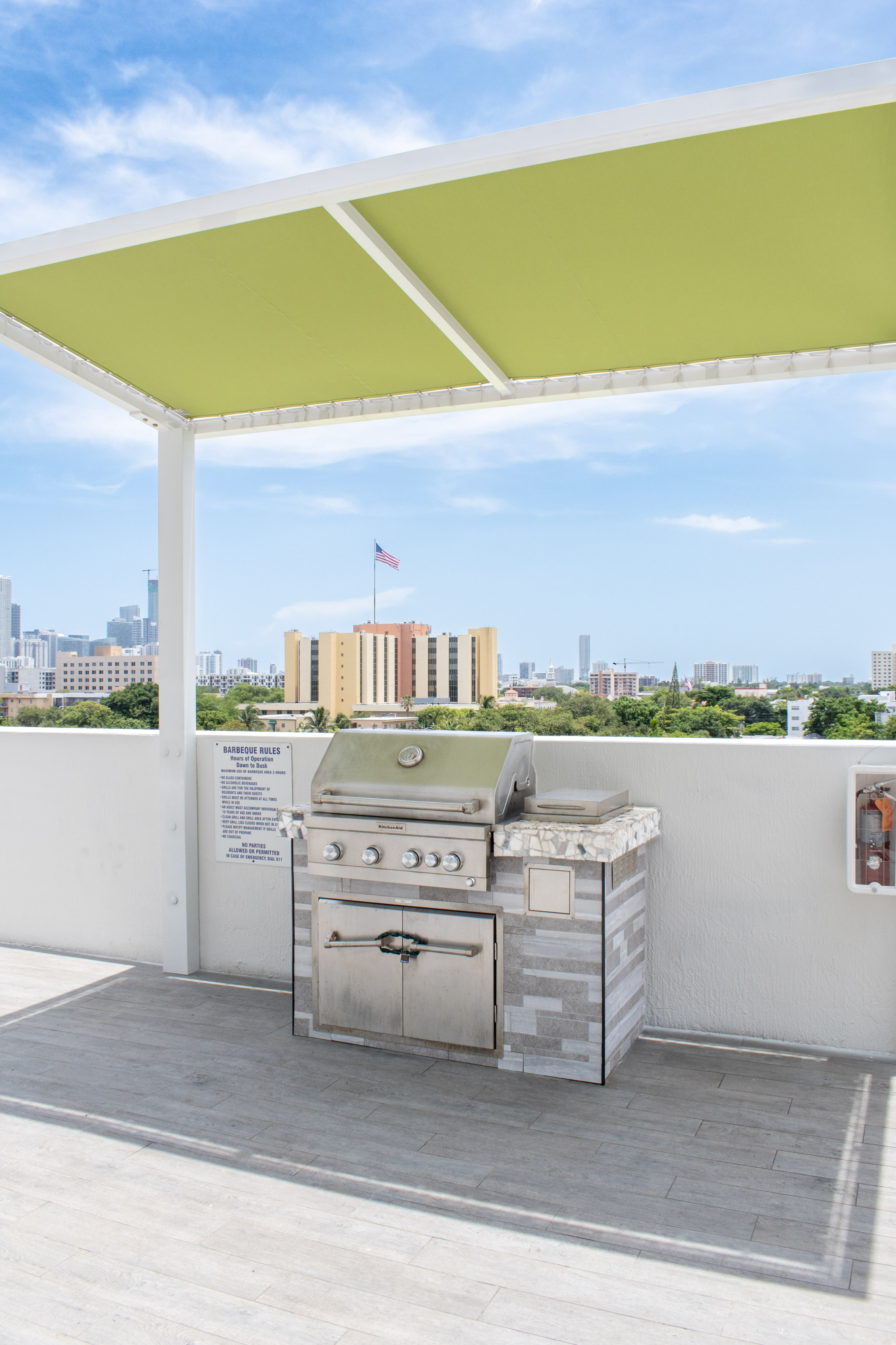 Rooftop terrace with modern barbecue grill, cityscape views, and a shaded seating area, offering a perfect urban retreat.
