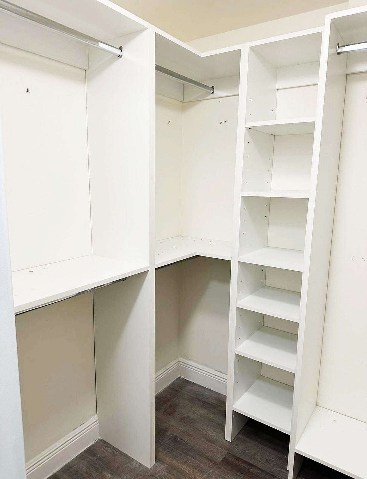 Spacious walk-in closet with sleek white shelving and ample hanging space, perfect for organized living.