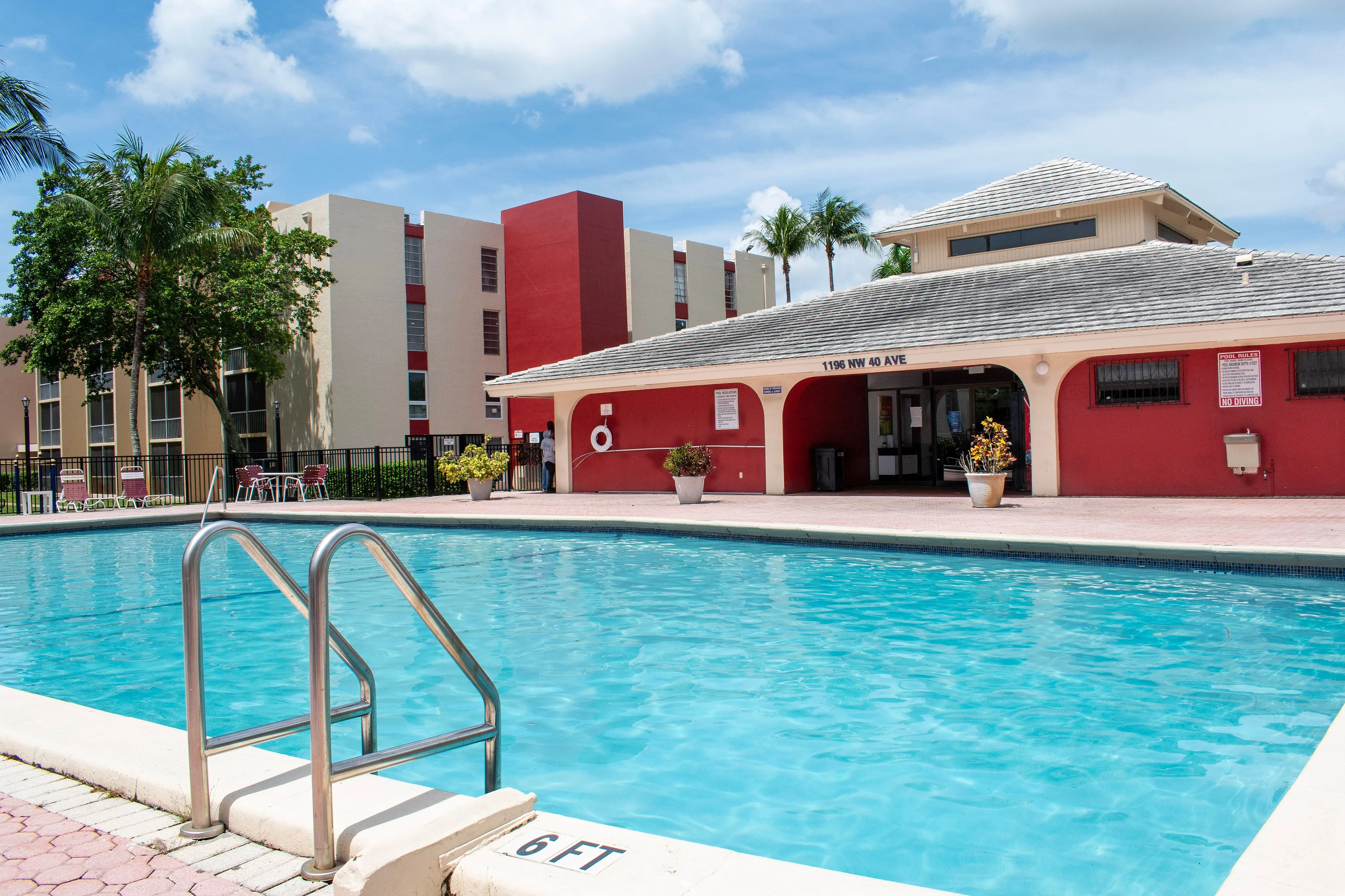 Inviting apartment complex features a vibrant pool area with crystal-clear water and modern lounging facilities, perfect for relaxation and leisure in sunny surroundings.