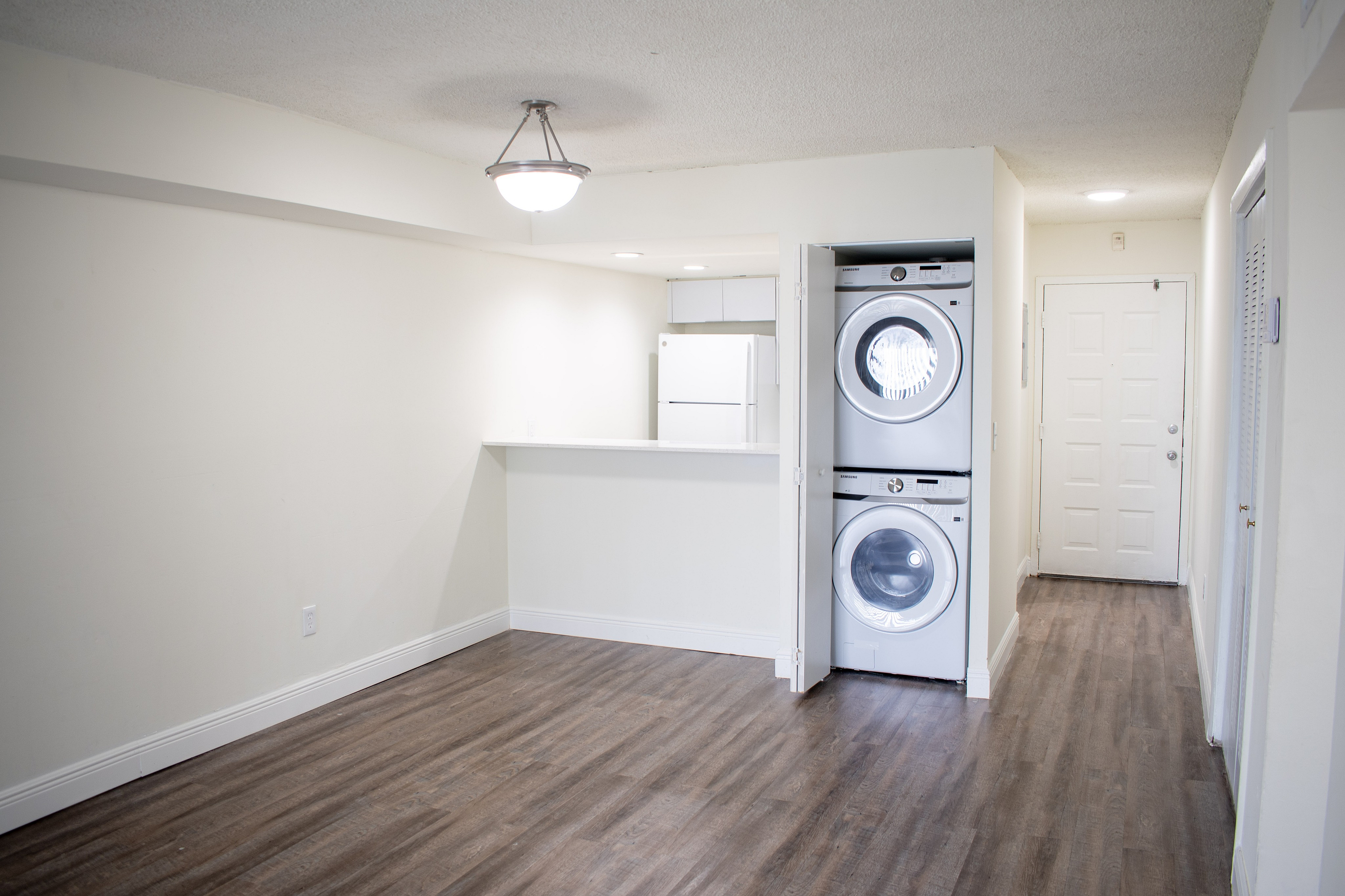 Modern apartment with elegant hardwood flooring, built-in washer and dryer, and a bright, compact kitchen featuring contemporary appliances.