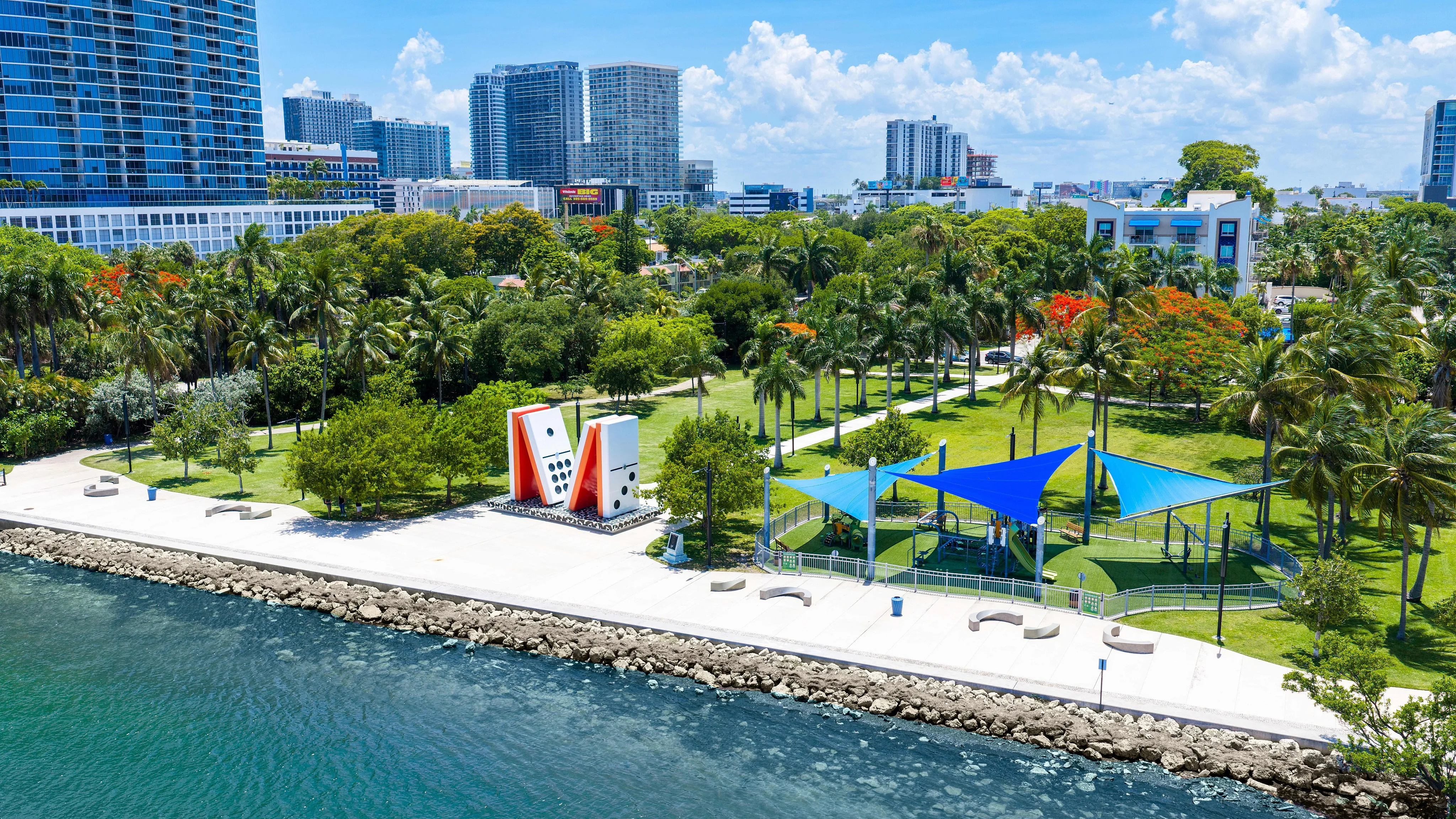 Vibrant waterfront park with modern art sculptures, lush greenery, and skyline views, perfect for urban relaxation.