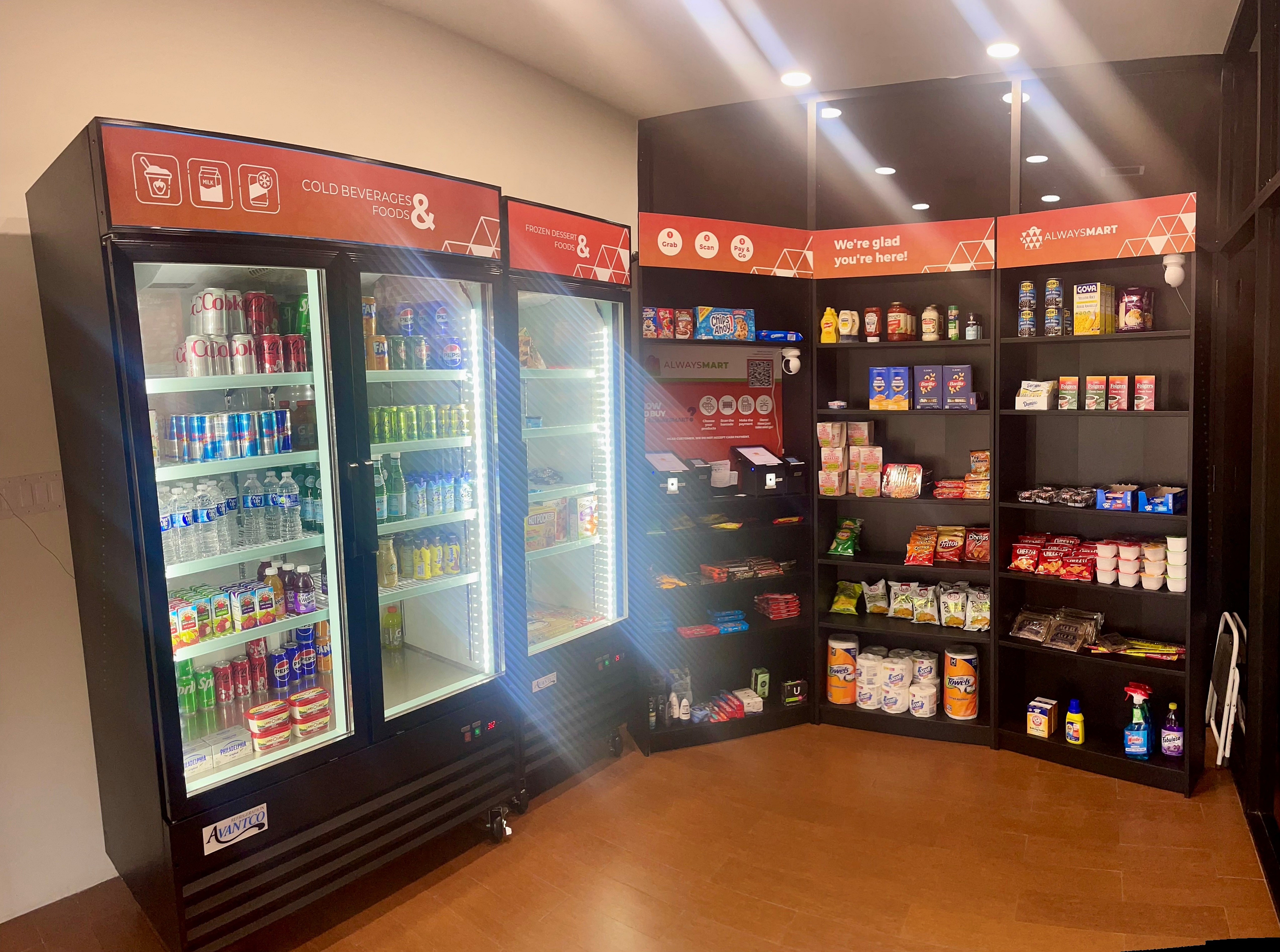 Modern convenience corner with stocked refrigerators and shelves, offering a wide variety of cold beverages, snacks, and essential groceries in a cozy setting.