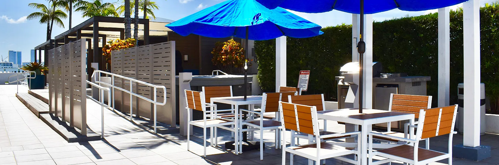 Chic outdoor terrace featuring vibrant blue umbrellas, stylish seating, and lush palm trees, perfect for relaxation and gatherings.