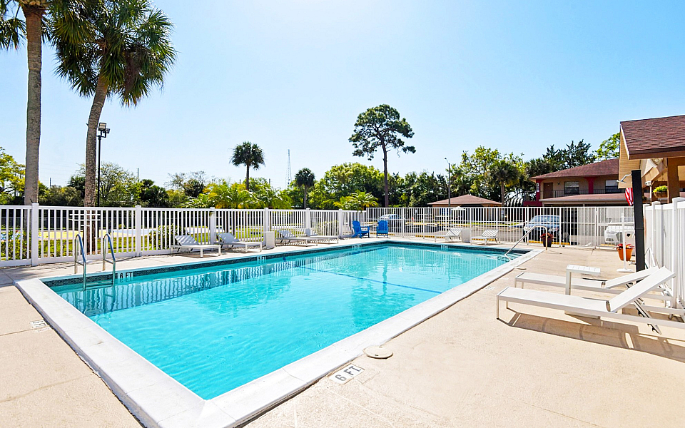 Inviting outdoor pool surrounded by lush greenery and lounge chairs, perfect for relaxing under the sun in a serene setting.