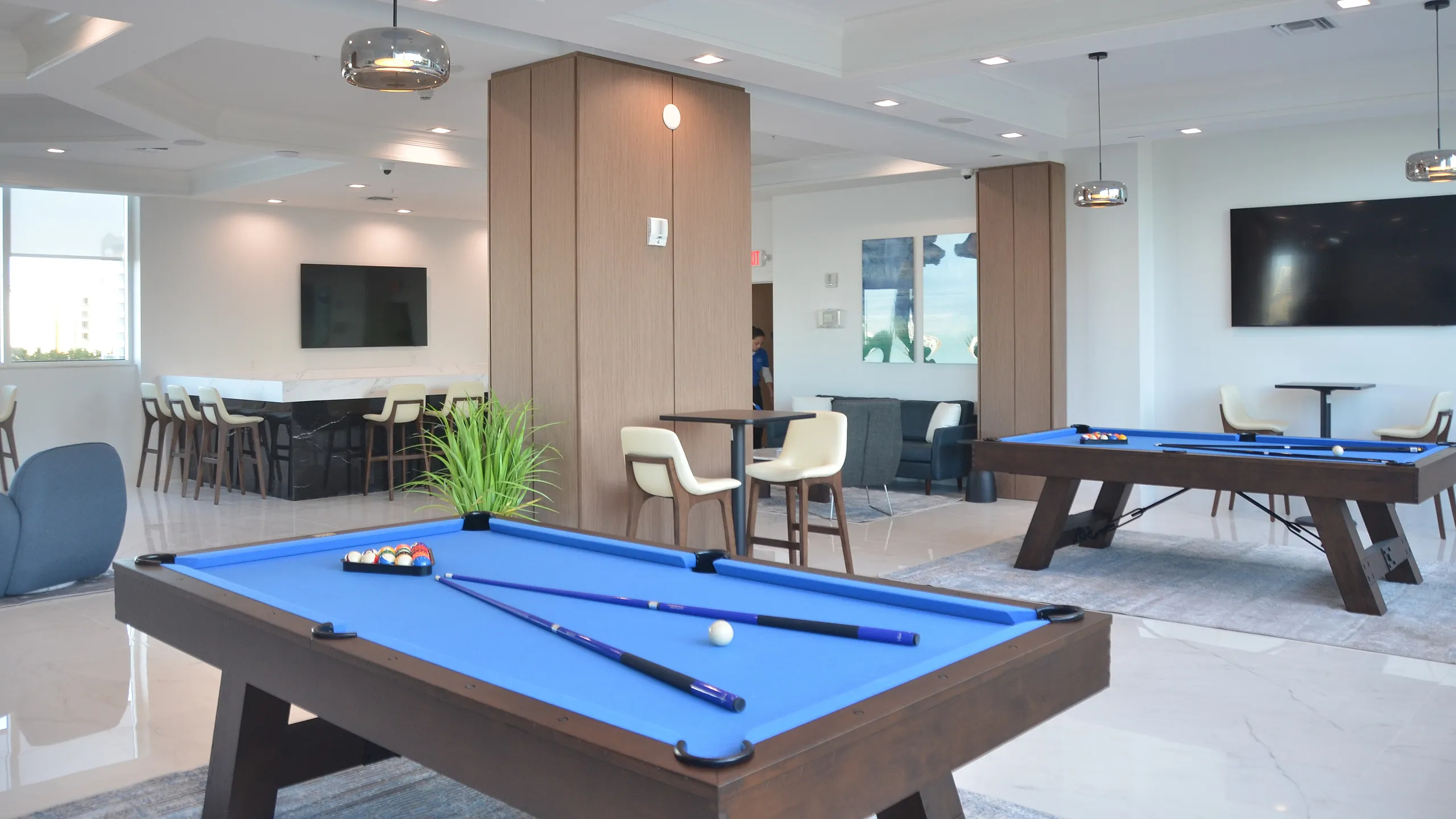 Elegant recreational room featuring modern pool tables, plush seating, and a sleek entertainment area.