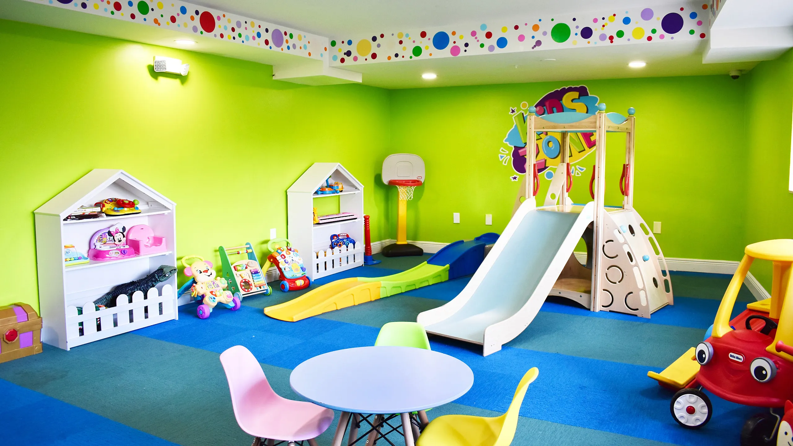 Vibrant children's playroom with colorful wall patterns, toys, and a mini slide, providing a fun and safe environment for kids.