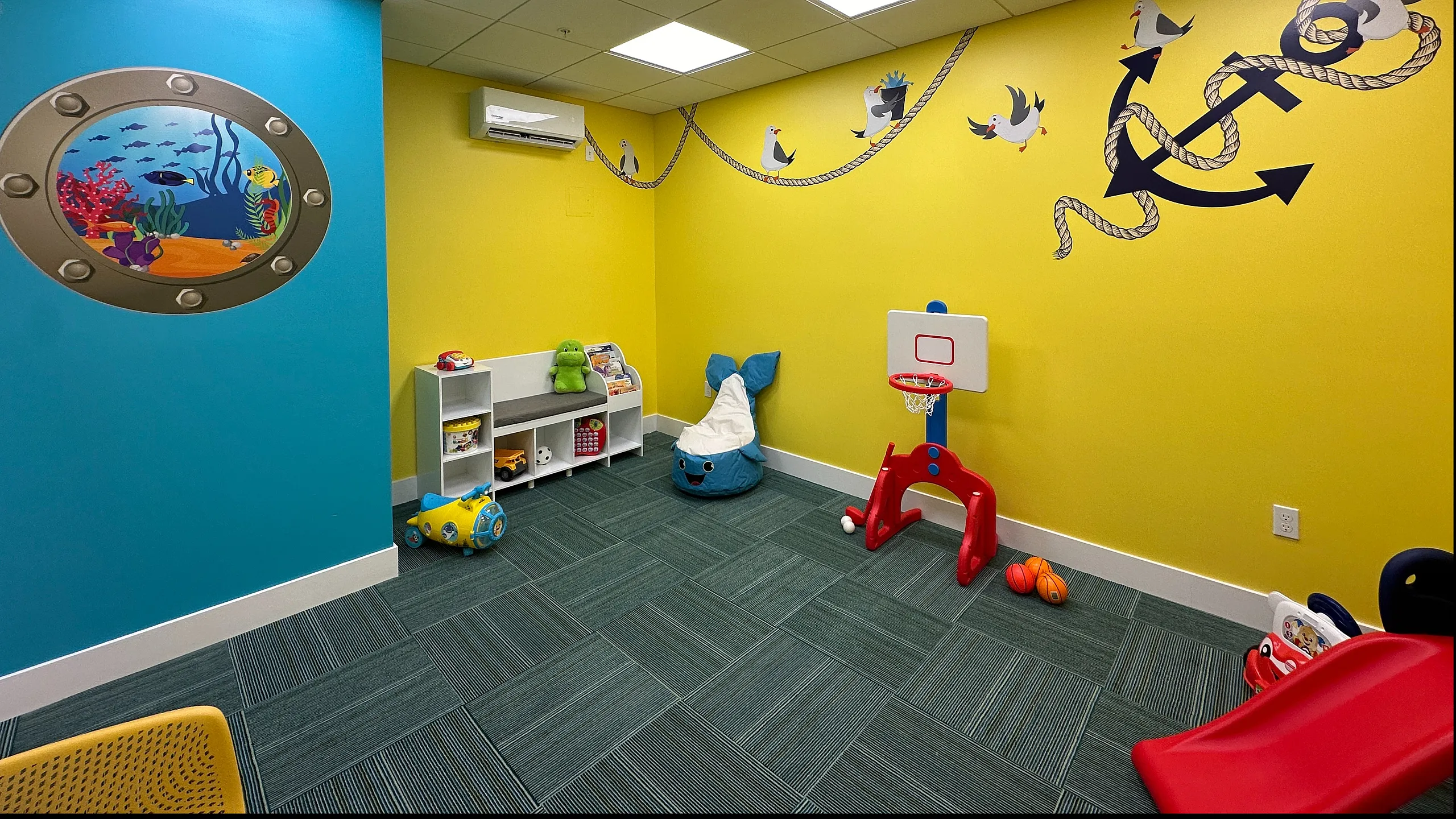 Vibrant kids' playroom with nautical theme, featuring colorful wall art, playful toys, and a mini basketball hoop.