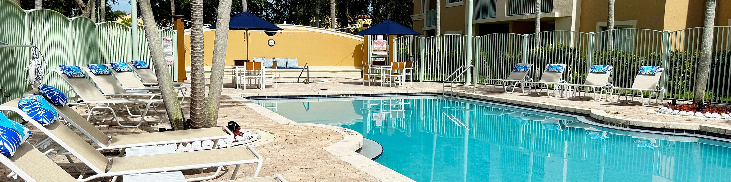 Inviting outdoor pool area with comfortable loungers, tropical palm trees, and a serene ambiance for relaxation.