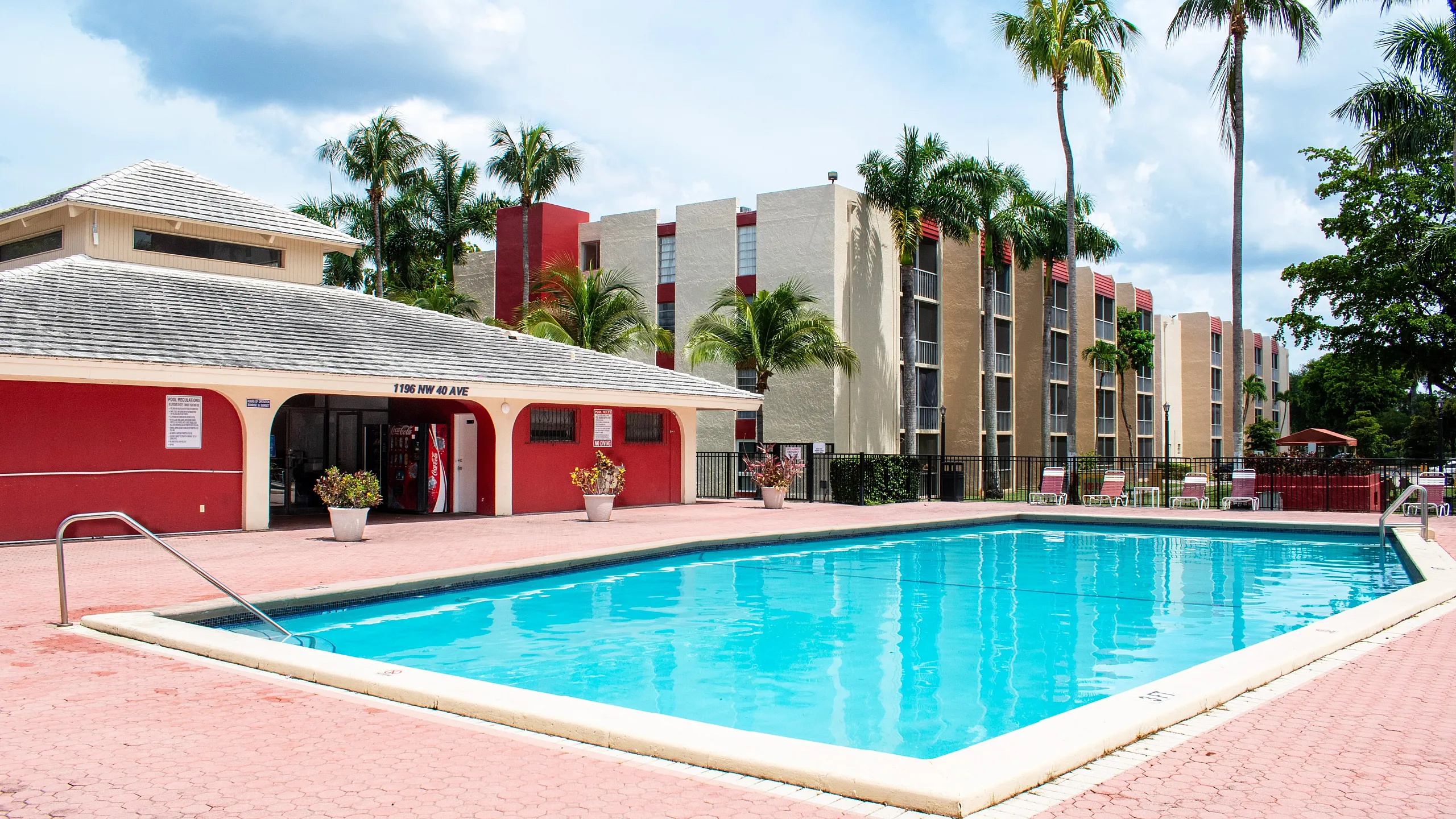 Inviting apartment complex with palm trees and a sparkling swimming pool, perfect for relaxation and leisure.